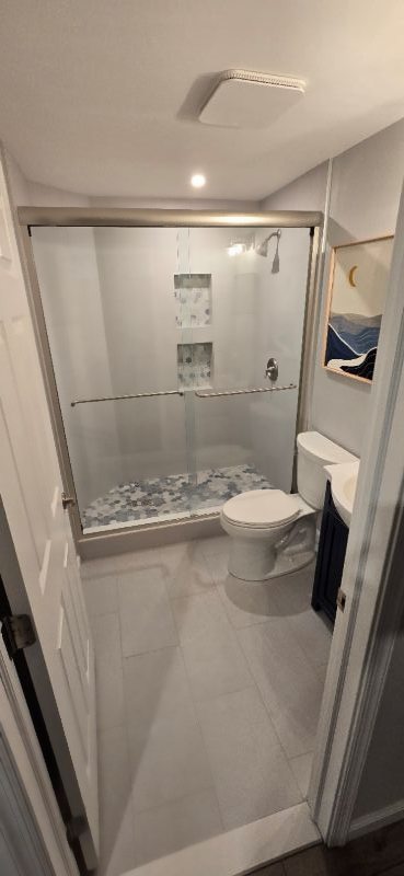 Finished basement bathroom with glass shower, mosaic tile floor, and custom vanity, built by Calvert Specialty Contracting in Southern Maryland