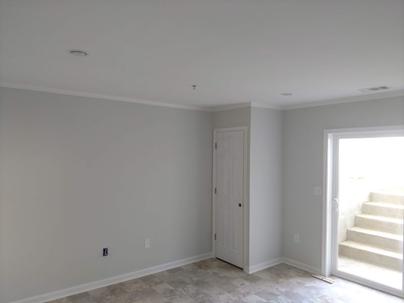 Finished basement with crown molding, tile floor, and walkout door in Calvert County, Maryland